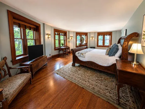 Full view of curved bedroom with five bay windows and king sleigh bed