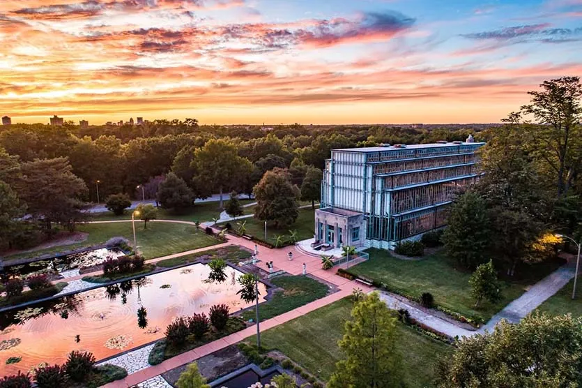 Aerial view of the Jewel Box conservatory in Forest Park at sunset, with reflecting pools in the foreground