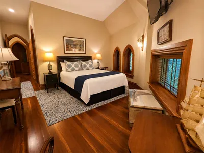 Riverfront Suite — queen bed with hardwood floors and stained glass windows