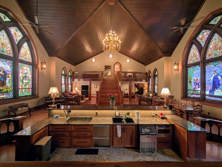 The sanctuary interior at Gothic Heights Inn showing stained glass windows, vaulted ceiling and common area