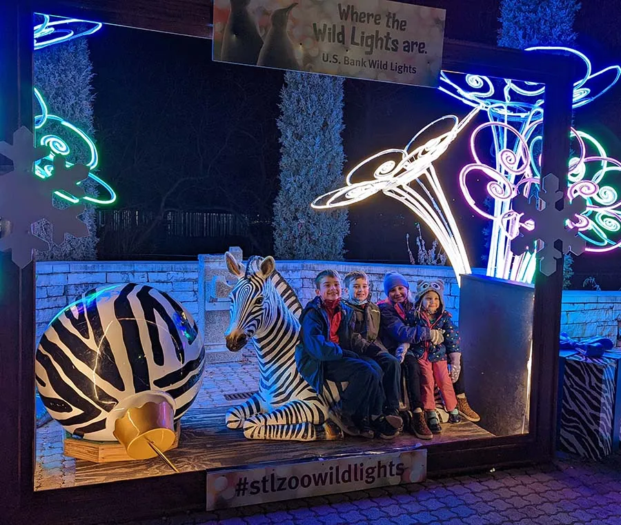 Kids posing with a zebra sculpture at the Saint Louis Zoo Wild Lights holiday event at night